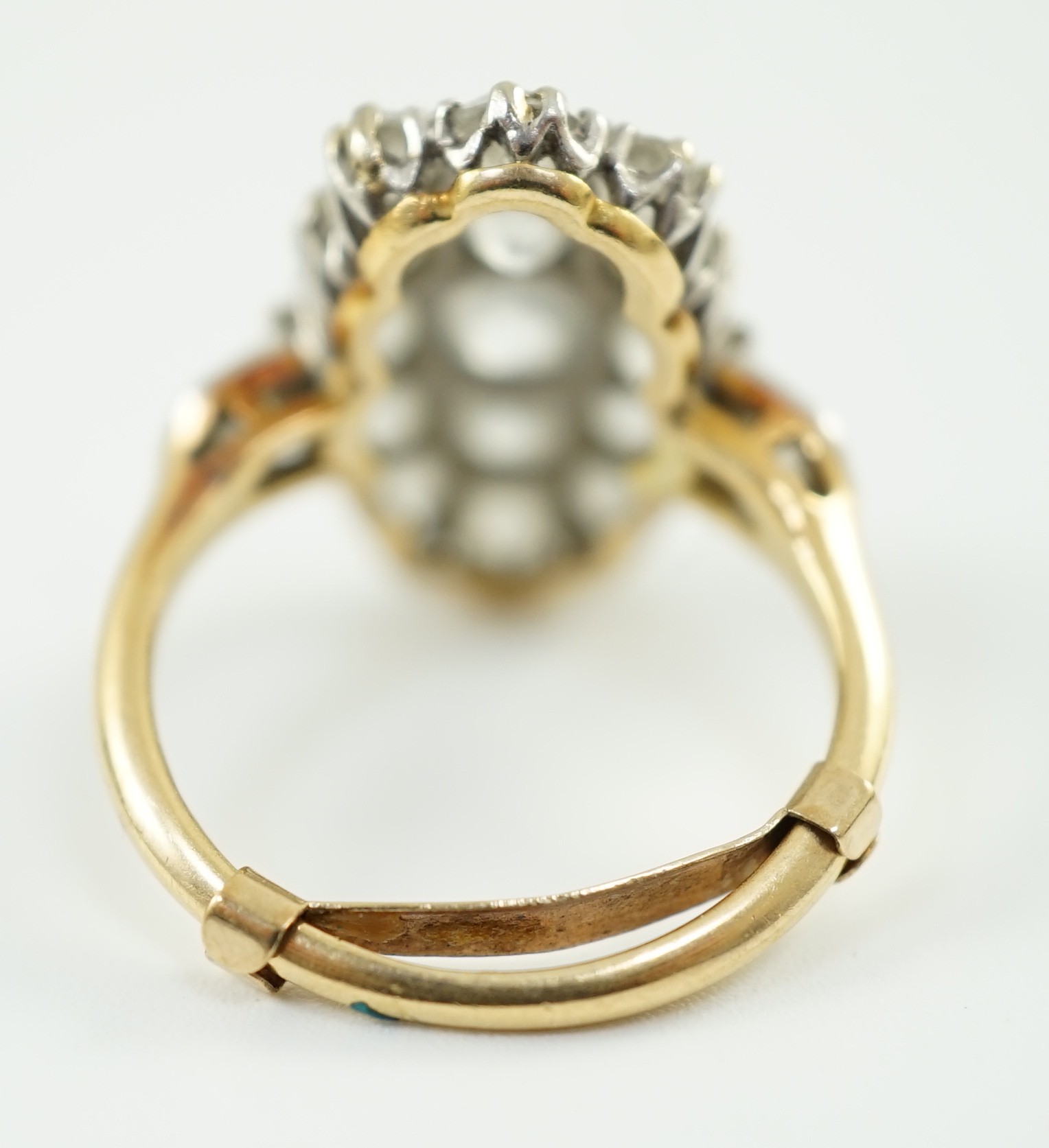 An 18ct gold and oval diamond cluster dress ring, with diamond set shoulders